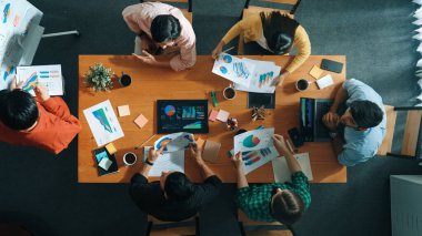 Akıllı iş adamlarının en iyi görüşü pazarlama fikrini toplantıda sunarken, bir grup yatırımcı da hisse senedi piyasası şeması veya veri analizine bakarken strateji dinleyip planlıyorlar. Üst Manzara. Cemaat.