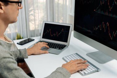 Stresli iş adamı günü modern ofisteki dinamik borsa grafiğine bakıyor, veri tabanı bilgisayarını ve bilgisayarını evden çalışırken karşılaştırıyor. Bireysel.