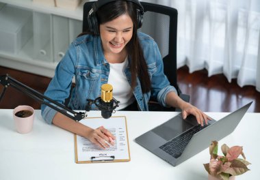 Sosyal medyada kulaklıkla canlı yayın yapan Asyalı sunucu modern stüdyoda yaşam koçluğu veya pazarlama dinleyicilerini selamlıyor. Taktik.