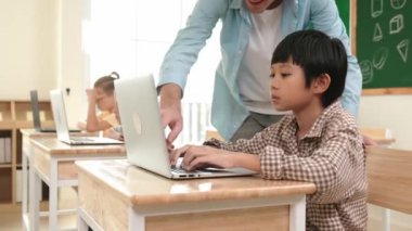 Kafkasyalı öğretmen Asyalı öğrenci kodlama mühendisliğine yardım ederken çeşitli öğrenciler yapay zeka yazılımı kullanıyor. Zeki, mutlu, çekici çocuklar, oturma ve programlama sistemi. Eğitim. Pedagoji.