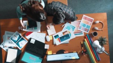 Akıllı tasarımcının renkli paletlerden renk seçmesine yardım ederken yukarıdan aşağı görünümü. Dizüstü bilgisayardan logoya bakarken birlikte çalışan ve planlayan iş adamlarının hava görüntüsü. Sempozyum.