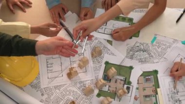 Mimari belge, ölçüm aracı ve ahşap blokların modern ofiste etrafa saçıldığı bir masa üzerinde yapı inşaatı ile ilgili mimar ve güvenlik mühendisi tartışması. Tanımlama.