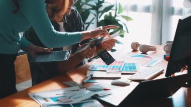 Akıllı tasarımcının renkli paletlerden renk seçmesine yardım ederken yukarıdan aşağı görünümü. Dizüstü bilgisayardan logoya bakarken birlikte çalışan ve planlayan iş adamlarının hava görüntüsü. Sempozyum.