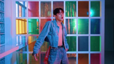 Kameraya bakarken kollarını esneten seksi kıyafetli Asyalı dansçı. Profesyonel sanatçı gece kulübünde renkli neon ışıkları canlı bir şekilde dururken serbest stil dansı yapıyor. Mutluluk.