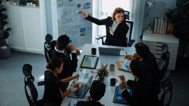 Akıllı yönetici projesinin üst görünümü beyaz tahtaya zihin haritası ve finansal grafik ile işaret ediyor ve çeşitli yatırımcılar hisse yatırım grafiğini dinleyip analiz ederken pazarlama fikrini açıklıyor. Müdürlük.