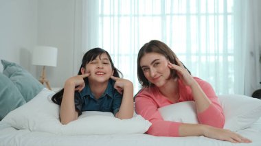 Mutlu Asyalı kız ve akıllı anne kameraya bakarken yatağa uzanıyorlar. Enerjik aile vakit geçirir ve birlikte yatmaya hazırlanır. Sevimli kız ve anne kameraya gülümsüyor sevgi ve şefkat gösteriyorlar. Pedagoji.