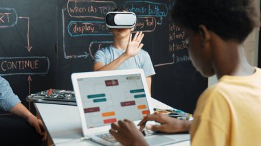 Kafkasyalı kız tahtada mühendislik kodlarıyla otururken Afrikalı erkek programlama sistemi. Liseli kız STEM teknolojisinde VR ya da kulaklık takıyor. Öğretim.
