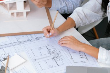 Profesyonel erkek mühendis ev modelini cetvel kullanarak ölçerken güzel bir iş arkadaşı da plan üzerinde yazarak birlikte çalışıyor. Yaratıcı tasarım ve takım çalışması. - Yakın çekim. Tertemiz..