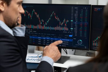 Dinamik borsada döviz kuru yatırımını tartışan iki ticaret simsarı iki bilgisayar ekranında gerçek zamanlı risk grafiği ya da modern ofisteki kar noktasını karşılaştırıyor. Varsayım.