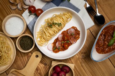 Lezzetli yiyecekler, ev yapımı spagetti, kıymalı domates sosu ve fesleğen fırlatma elementleri, şef masası dekoratif baharatlarla servis ediliyor. Varsayım.