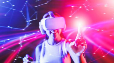 Zeki bir kadın, metaevreni birbirine bağlayan VR kulaklık takan neon ışıklarla çevrili duruyor. Gelecekteki siber uzay topluluğu teknolojisi. Sanal objeye parmağını kullanan zarif bir kadın. Halüsinasyon.