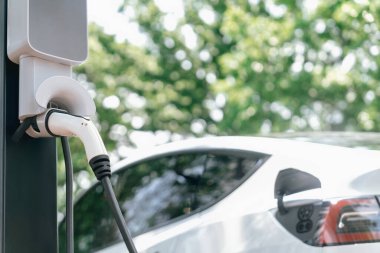 EV elektrikli araç EV şarj istasyonu ulusal park veya açık hava orman manzaralı. Çevre dostu EV arabalarla yaz ormanlarında doğal koruma. Yükselt