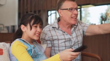 Büyükbaba ve torun birlikte TV 'de ilginç bir eğlence medyası izliyorlar. Eski üst düzey kullanım teknolojisi, genç nesil çapraz nesil ile iletişim kurarak aile bağlarını güçlendiriyor. Uyumsuzluk.