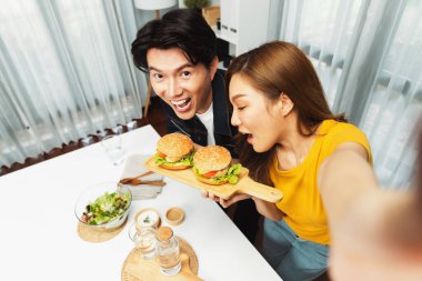 Gülümseyen ev sahibi aşçıların akıllı telefonuyla fotoğraf çekerken üst görüntüsü yemek programında çift hamburger tutarken sosyal medya kanalında ev yapımı salata tabağıyla kolaylıkla görülebiliyor. İnfobahn.