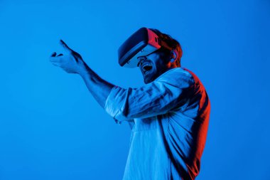 VR cam takan ve hareket eden el kol tabancası tutan bir adamın yan görüntüsü. Oyuncu, gelecekteki sanal gerçeklik kulaklığını ya da gelecekteki yenilikleri kullanarak meta dünyaya giriyor ya da aksiyon oyunu oynuyor. Sapma.