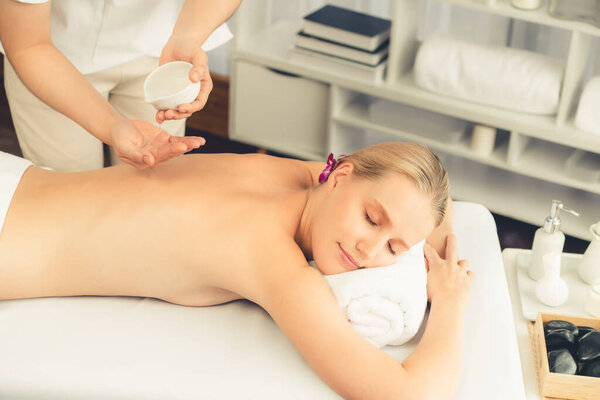 Массажист выливает ароматное масло на спину женщине. Массажист готовит масляный массаж для клиента в спа-салоне на роскошном курорте. Концепция массажа тела с ароматическим маслом. Quiescent