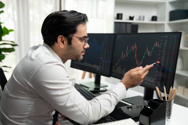Akıllı tüccar işadamı, modern merkez ofisindeki araştırma pazarında en yüksek kârlı finansal teknolojiye yatırım yaparak bilgisayar üzerinde iki dinamik borsa yatırım ekranını analiz ediyor. Tahmin et..