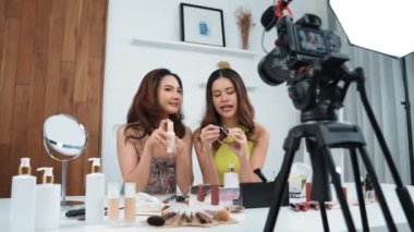 İki kadın nüfuzlu partner sosyal medya veya blog için canlı yayın yapan video klip inceleme derisi çekiyorlar. Canlı kozmetik stüdyo ışığı olan genç bir kız çevrimiçi pazarlama kayıt oturumu yayını için.