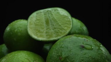 Limon dilimleri titizlikle bir yığın halinde, siyah arkaplana göre dizilmiş. Her bir kireç dilimi çarpıcı detaylar, canlı yeşil rengi ve baştan çıkarıcı dokusu ile yakalanır. Kapatın. Geliştirilebilir.