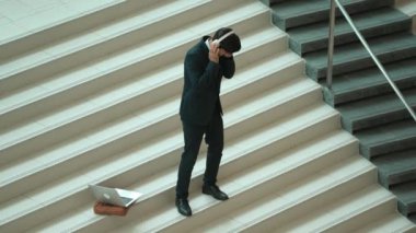 Kulaklıktan müzik eşliğinde merdivenlerde duran profesyonel bir iş adamı. Merdivenlere dizüstü bilgisayar yerleştirip dans ederken dinlenme sesi dinleyen yetenekli bir proje yöneticisi. Modern dans. Sevinçli..