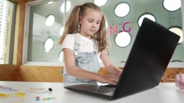 Kameraya bakıp gülerken dizüstü bilgisayar programlama yazılımı kullanan tatlı bir kız. Güzel çocuk gülümserken Stem sınıfında komik masum ruh halinden vazgeçiyor. Akıllı öğrenci portresi..