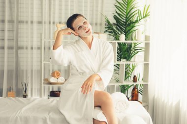 Kaplıca salonunun sakin, modern gün ışığı atmosferi, kadın müşteri poz veriyor ve yüz maskesi ile gençleştiriyor. Yüz bakımı ve güzellik kozmetolojisi prosedürü. Sessiz.