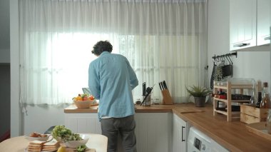 Mutlu baba yemek pişirirken müziğe geçiyor ve modern mutfakta öğle yemeği hazırlıyor. Aktif baba, sebze ve mutfak gereçleri ile çevrili sağlıklı yemek ya da salata yaparken şarkıyla dans ediyor. Pedagoji.