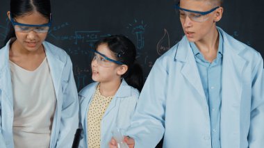 Zeki kız deney yapmak için heyecanlanan çeşitli öğrenciler iken beher kabına renkli solüsyon döker. Profesyonel bilim adamı kimyasal teoriyle kara tahtada deney yapmaya hazırlanıyor. Öğretim.