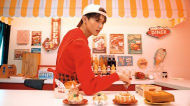 Profesyonel Asyalı restoran işçisi yemek hazırlar ve yemek barının arkasında durur. Kırmızı gömlekli ve kırmızı önlüklü mutlu garson kameraya bakarken serbest stil müziğe geçiyor. Çılgın dans. Mutluluk.