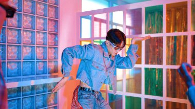 Ortasında dans eden profesyonel mutlu hipster onu alkışlayan çeşitli arkadaşlarıyla dans ediyor. Çekici Asyalı kırığı gece kulübünde neon ışığıyla enerjik adımlar atıyor. Mutluluk.