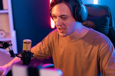 Oyun kanalı, online oyun oynayan akıllı flamalı oyun sunucusu, kulaklık takan, neon ışıklandırma odasındaki takım oyuncusuyla akıllı telefondan canlı yayında konuşan izleyiciler. Bireysel.