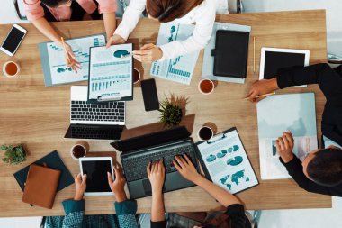 Modern ofisteki iş adamları ve iş kadınlarıyla grup toplantısındaki iş adamlarının en üst düzey görüşü, masada dizüstü bilgisayar, kahve ve belge ile. Kurumsal şirketler uds