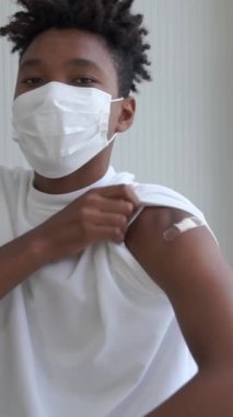 Afrikalı Amerikalı genç COVID-19 aşısı gösteriyor. Koronavirüs aşısı konseptiyle neşeyle sargılanıyor. Vatandaşı aşılamak için. .