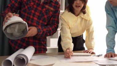 Mimari döküman, ölçüm araçları ve ahşap blokların modern ofiste etrafa saçıldığı masa üzerine planlar yapma konusunda akıllı mimar ve güvenlik mühendisi tartışması. - Yakın çekim. Tanımlama.