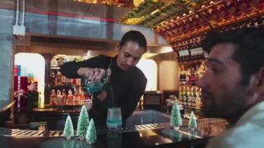 Barmen soğutma bardağına karışık mavi lagün kokteyli dökerken, misafirler içki bekleyen arkadaşlardan bahseder, çam ağacından yapılmış Noel temalı süslemeler özel şenlik tatlandırıcılarını çiftleştirir. Vinosity.