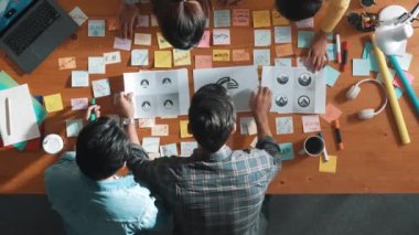İşletme ekibinin üst görüntüsü toplantı masasına renkli yapışkan notlar ve tasarım ile grafik logo yazarak fikri açıklar. Proje yöneticisi fikri paylaşıyor ve akıllı takıma konsept sanatı anlatıyor. Sempozyum.