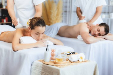 Sıcak bitkisel top spa masaj vücut tedavisi, masör nazikçe bitki torbasını çift müşteri vücuduna bastırıyor. Aromaterapi dinlenme sükuneti ve sükuneti kaplıca salonundaki atmosferi aydınlatıyor. Sessiz.