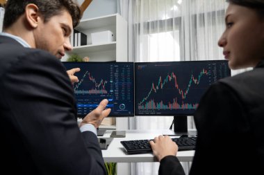 Dinamik borsada döviz kuru yatırımını tartışan iki ticaret simsarı iki bilgisayar ekranında gerçek zamanlı risk grafiği ya da modern ofisteki kar noktasını karşılaştırıyor. Varsayım.