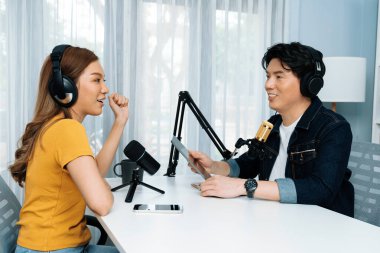 Gülümseyen radyo etkili sunucu elinde tablet, kulaklık takıyor kadın konuşmacı sosyal medya online canlı yayın kanalı ile röportaj yapıyor ve sabah stüdyo kaydında paylaşım linkini paylaşıyor. İnfobahn.