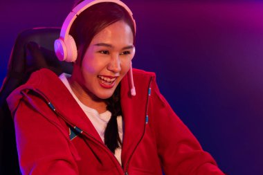 Portre sunucusu güzel Asyalı kız flamasının çevrimiçi oyun oynaması kulaklık takması pastel renkli konuşmalar izleyici medyası ile çevrimiçi. Esport yetenekli takım oyuncuları neon mavi odada. Taktik.