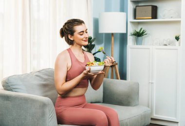 Spor giyimli sağlıklı ve vejetaryen bir kadın bir kase meyve ve sebzeyle. Sağlıklı beslenme ve spor için vejetaryen yaşam tarzı ev konseptinde vücut fiziği.