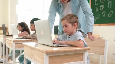 Çeşitli öğrenciler yapay zeka yazılımı kullanırken, Kafkas öğretmeni enerjik çocuğa kodlama konusunda yardım ediyor. Çocuklar oturma ve programlama sistemi. Sevimli bir öğrenci şifreyi öğreniyor. Pedagoji.