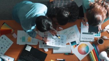 Tasarımcı fikirleri yazarken proje yöneticisinin yukarıdan aşağıya bakan görüntüsü. Akıllı iş adamları logo tasarımı fikrini açıklarken tasarımcılar palete bakarken temayı seçiyorlar. Sempozyum.