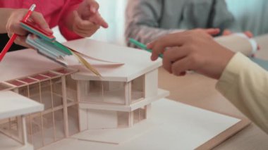 Mimari ekipman kullanarak yavaş çekim ev tasarımcısı bir plan çizerken, iç mimari tasarımcı da müşterilerin talebine göre renk örneklerinden uygun renkler seçiyor. Değiştirilmiş