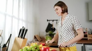 Kafkaseli anne kahvaltıda sebze pişirirken mutlu anne de modern mutfakta salata için taze malzemeler hazırlıyor. Hizmetçi sağlıklı yemek pişiriyor. Dikkat konsepti. Pedagoji.