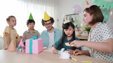 Kafkasyalı anne doğum günü pastasını kesiyor ve babaya verirken tatlıyı ayırıyor. Mutlu aile, kızının doğum gününde masada otururken parti şapkası takar. Özel durum konsepti. Pedagoji.