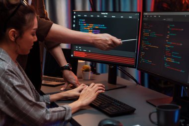 Bilgi teknolojisi geliştiricileri modern ofisteki neon ışık odasında verileri çevrimiçi olarak çalıştıran akıllı web sitesi geliştirme kodlayıcı sistemine işaret ediyorlar. İnfobahn.