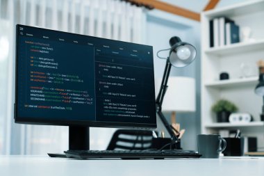 Bilgisayar ekranındaki programlama kodu çalışma masasına yerleştirilmiş akıllı web sitesi geliştirme kodlayıcı sisteminin veri tabanını bilgi teknolojisi tasarım konseptiyle çevrimiçi çalıştırdığını gösteriyor. İnfobahn.