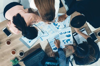 Modern ofisteki iş adamları ve iş kadınlarıyla grup toplantısındaki iş adamlarının en üst düzey görüşü, masada dizüstü bilgisayar, kahve ve belge ile. Kurumsal şirketler uds