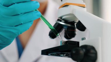 Laboratuvar kimya araştırmacısı mikroskop kullanarak yeni ilaç ya da tedavi geliştirir. Laboratuvar mikrobiyoloji ekipmanları ile bilimsel uzmanlık ile sağlık hizmetlerinin teknolojik gelişimi. Ağır çekim. Katı.